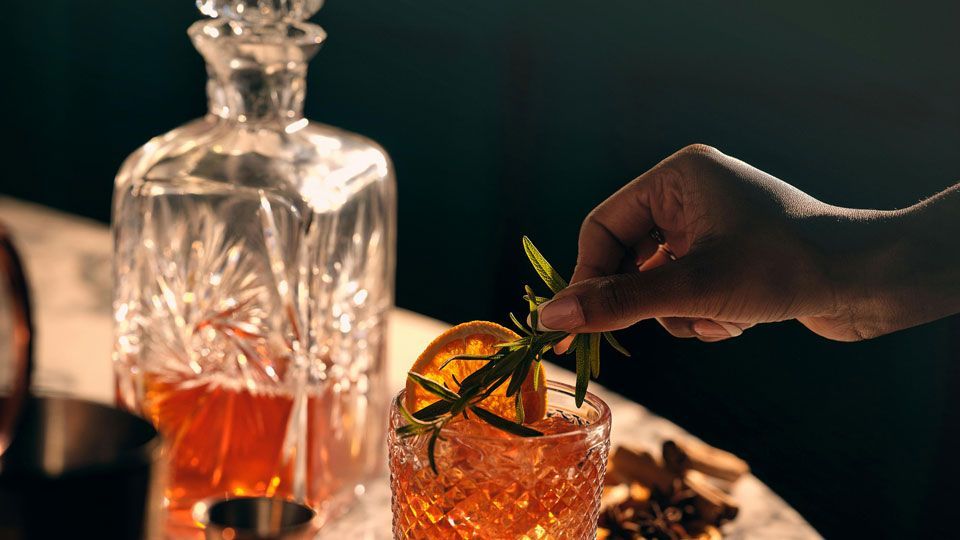 Dégustation de spiritueux au bar Maison Amour à Tours, servi dans un verre en cristal avec zestes et herbes aromatiques